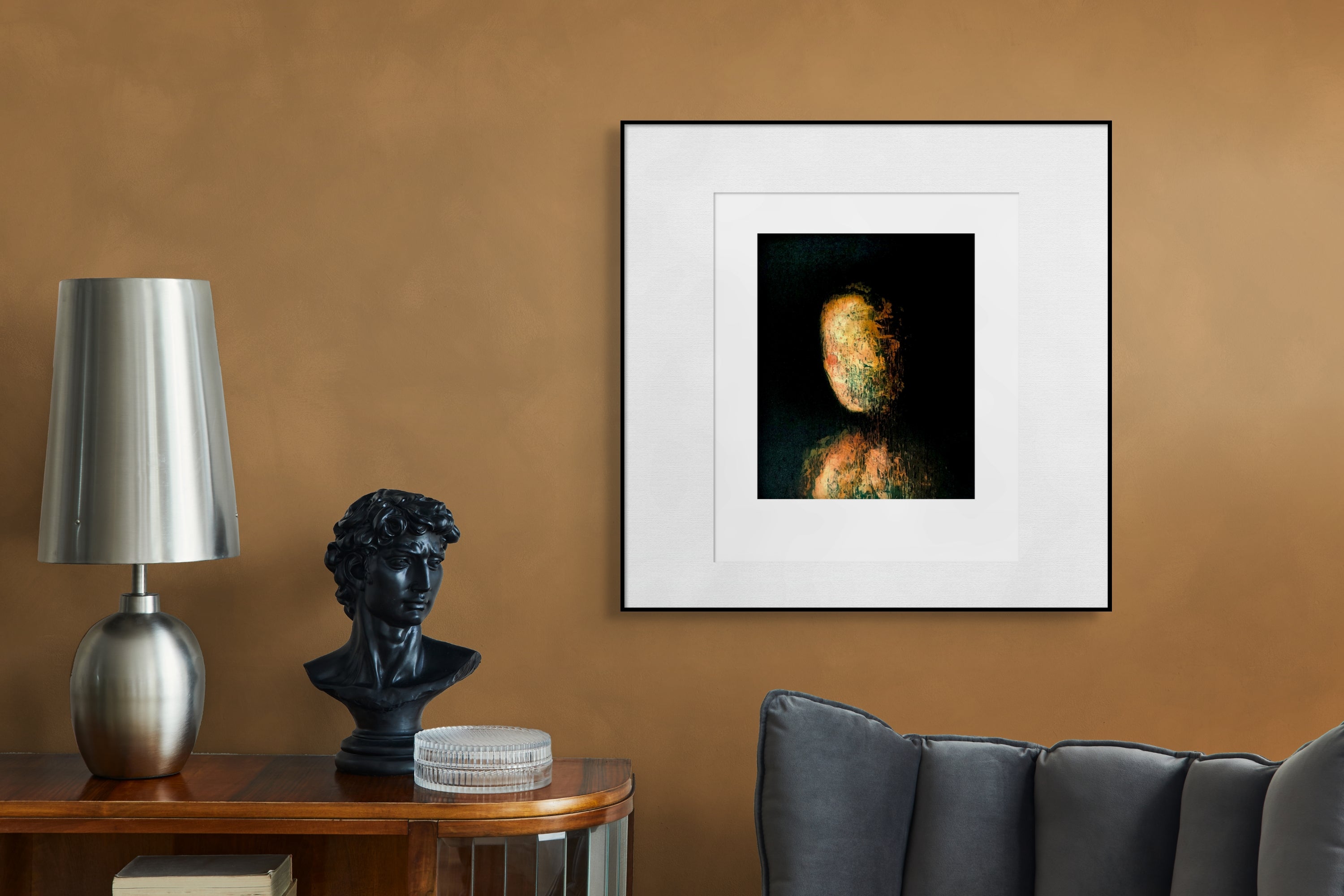 Gerahmte Radierung "Judith" von Stephen Lawlor – Gerahmtes Bild in Schwarz mit weißem Passepartout an ockerfarbener Wand über Sideboard mit Lamp.