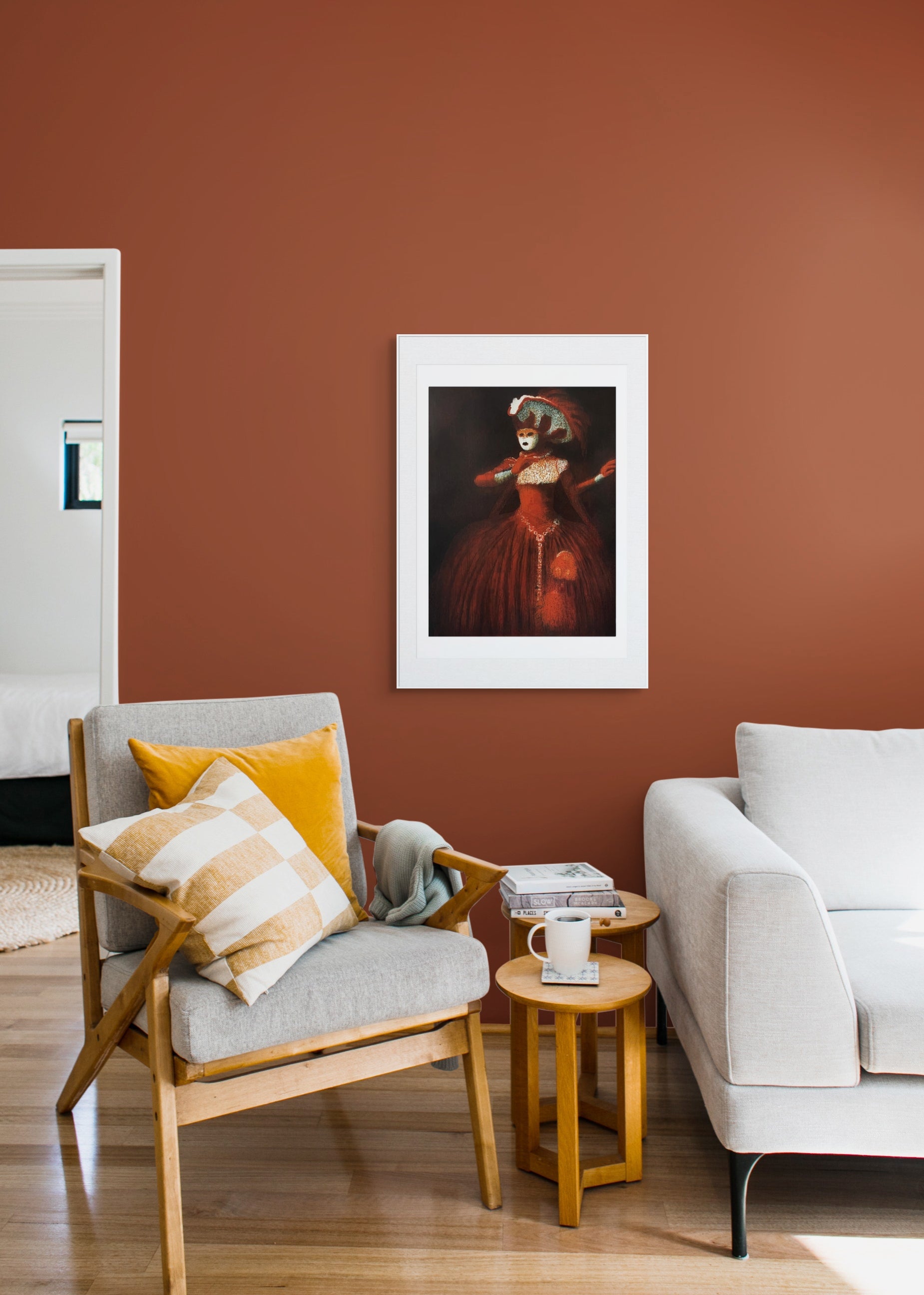 Gerahmte Radierung "Venetian" von Stephen Lawlor – Gerahmtes Bild an rostbrauner Wand zwischen Grausofa und Sessel mit gelben und karierten Kissen.