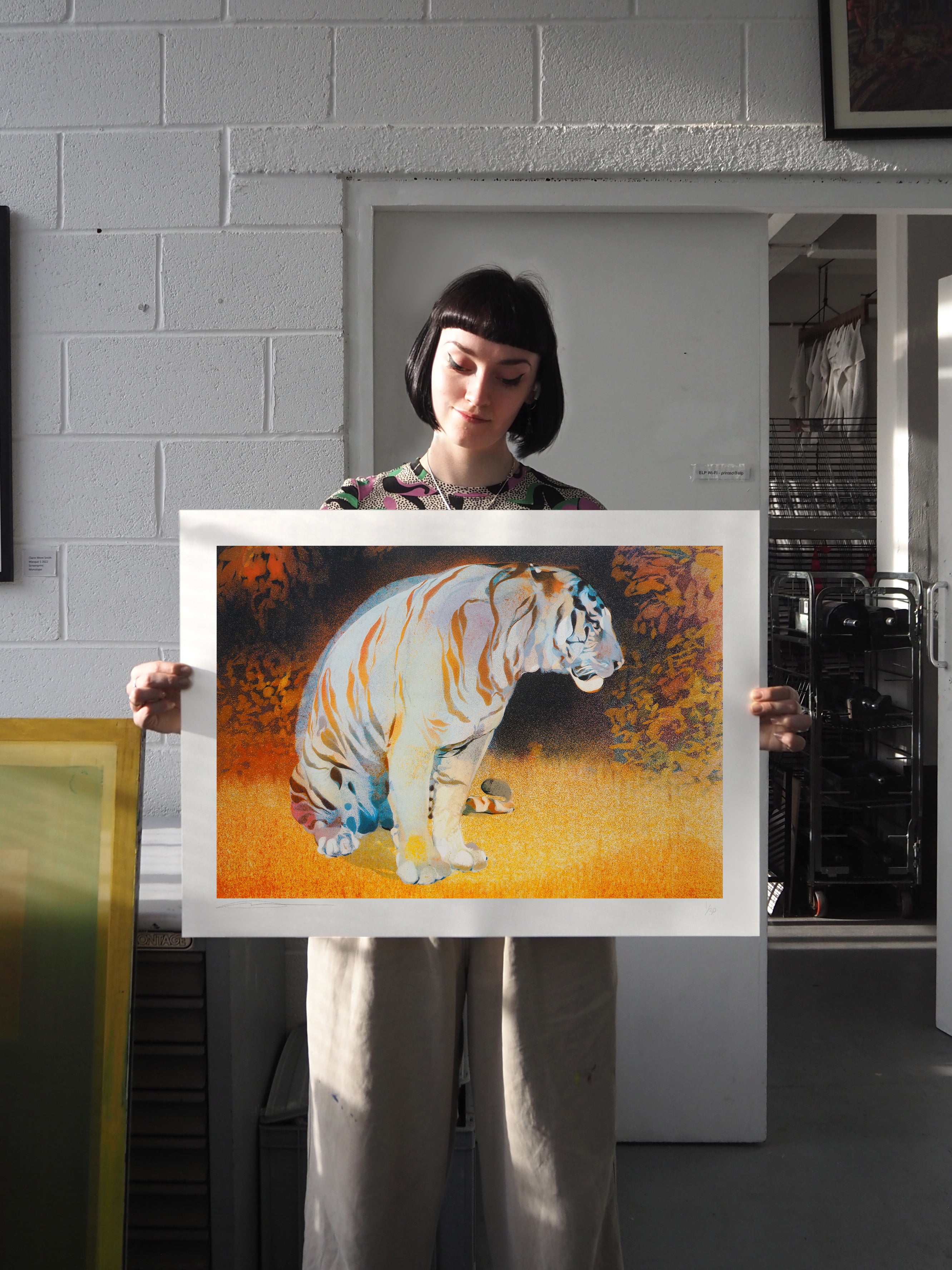 Detail: Person hält querformatigen Druck mit Tigermotiv in Werkstattumgebung. Siebdruck "Tiger in the Bear Rainforest" von Georgia Green.